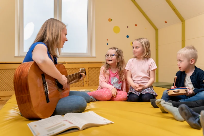 Kinderbetreuerin mit drei Kindern beim Musizieren im Waldviertel